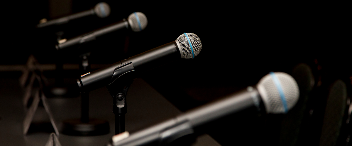 Microphones set up on a black backdrop in preparation for a candidates' debate